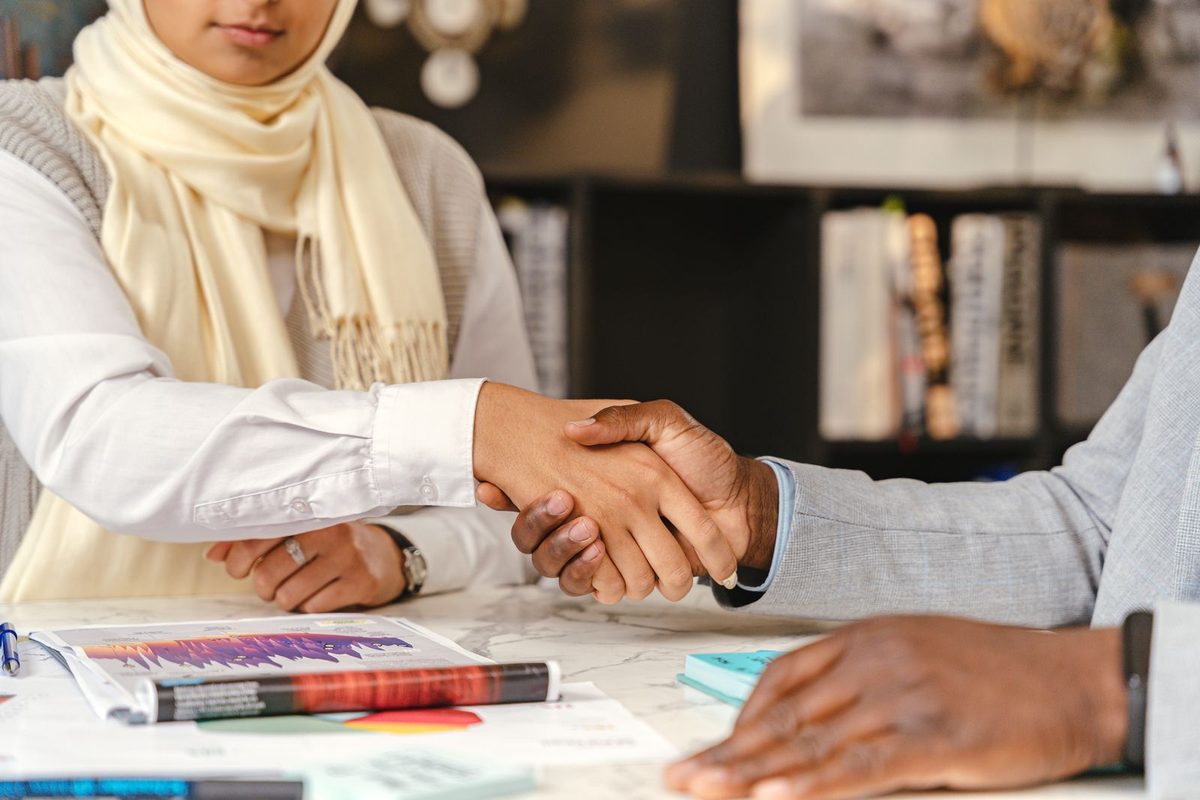 Two professionals shaking hands over reports on a table